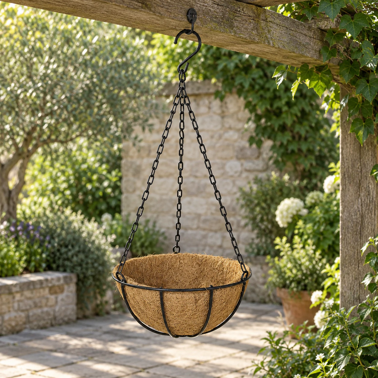 Empty 30 cm coir hanging basket secured to a timber pergola in an established garden
