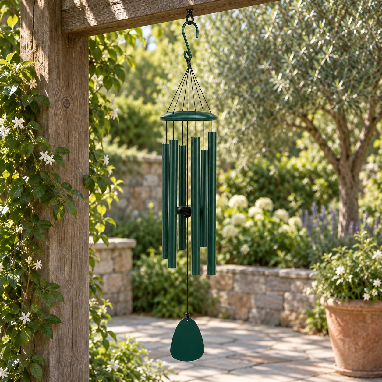 Forest green six-tube wind chime secured beneath a timber pergola in an established garden